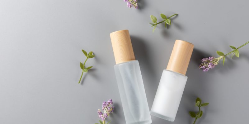 A top view of skincare bottles on a surface with lavender flower